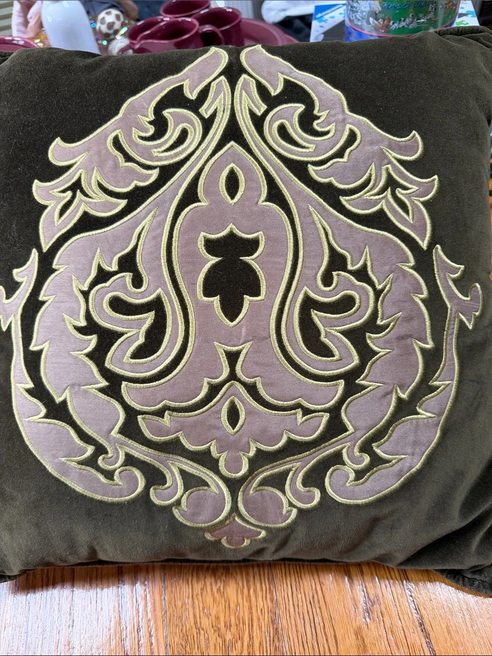 Reba green velour pillow with embroidered scroll design on front.